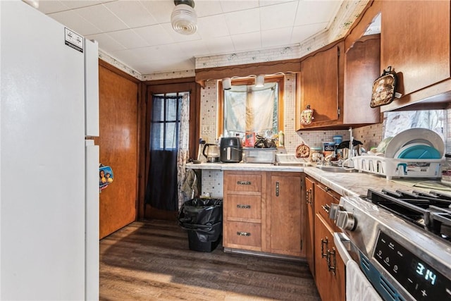 kitchen with dark wood finished floors, light countertops, brown cabinetry, and gas stove