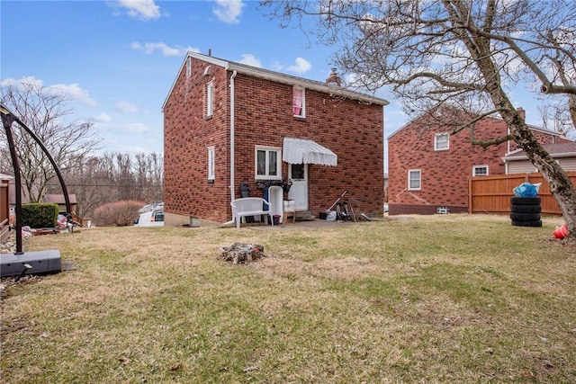 back of property featuring brick siding, a lawn, a chimney, and fence