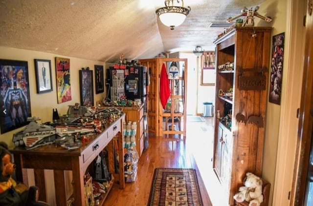 interior space with lofted ceiling, a textured ceiling, and wood finished floors