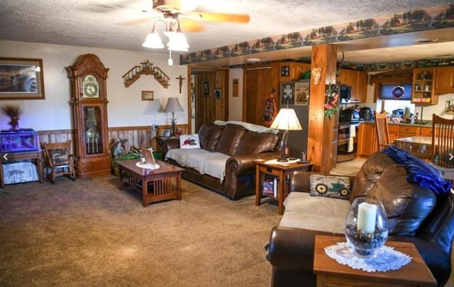 carpeted living area with wainscoting, a textured ceiling, and a ceiling fan