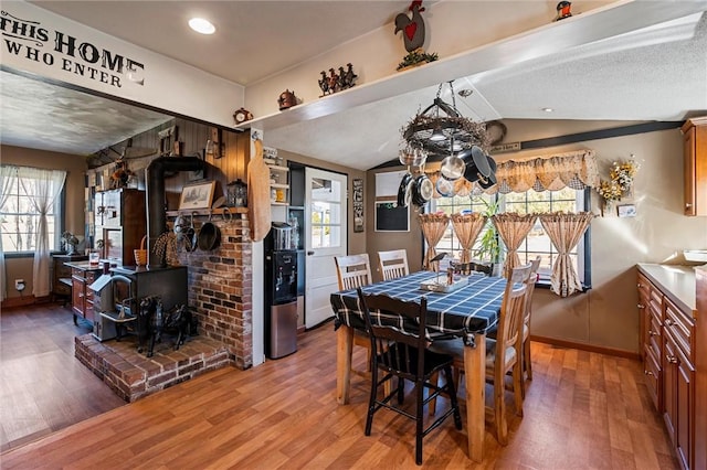 dining area featuring a wood stove, plenty of natural light, and wood finished floors