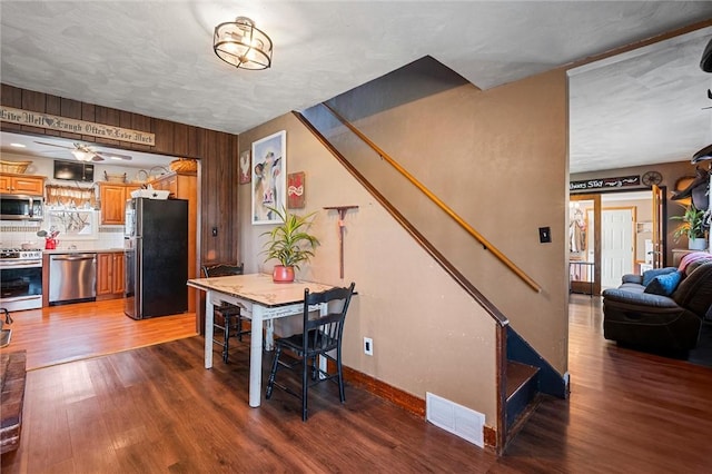 dining room featuring visible vents, baseboards, stairs, wood finished floors, and a ceiling fan