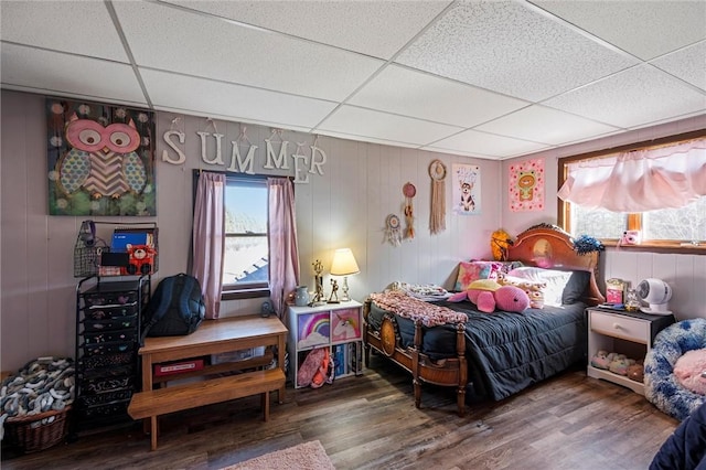 bedroom with a paneled ceiling and wood finished floors