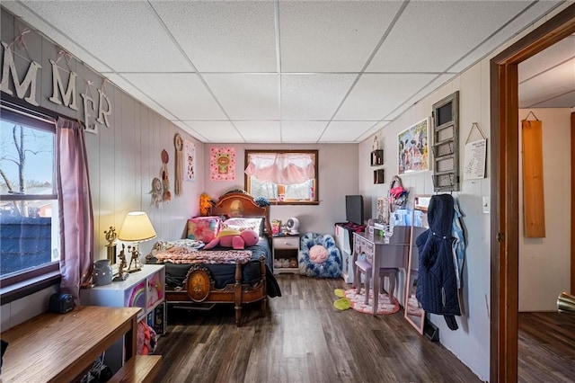 bedroom with a drop ceiling, multiple windows, and wood finished floors