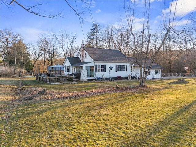 back of house featuring a wooden deck, a lawn, and a chimney