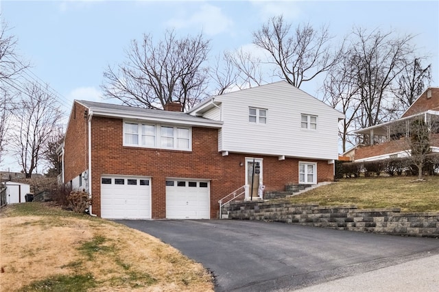 split level home with a front lawn, aphalt driveway, an attached garage, brick siding, and a chimney