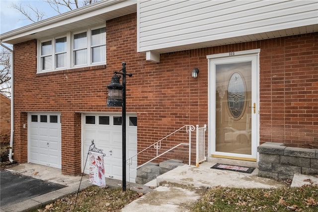 property entrance with driveway, brick siding, and an attached garage