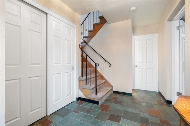 stairway featuring stone tile flooring and baseboards