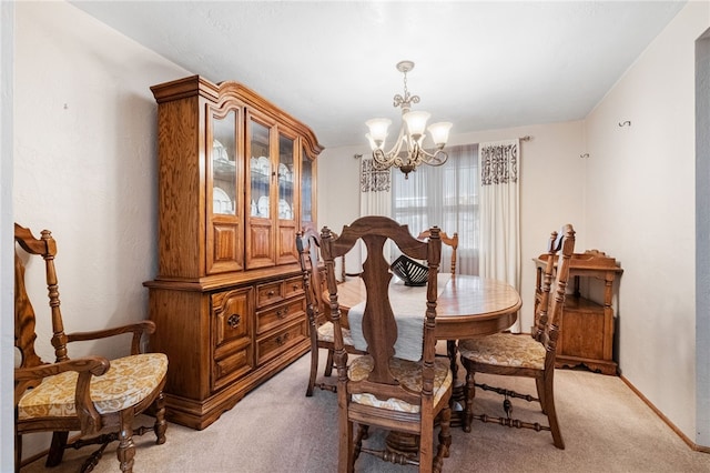 dining area featuring a notable chandelier, light colored carpet, and baseboards