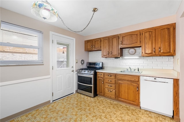 kitchen featuring a sink, double oven range, light countertops, light floors, and dishwasher