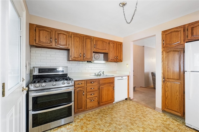 kitchen featuring brown cabinetry, white appliances, light countertops, and a sink