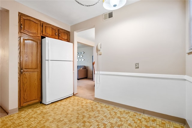 kitchen with light floors, baseboards, visible vents, freestanding refrigerator, and brown cabinets