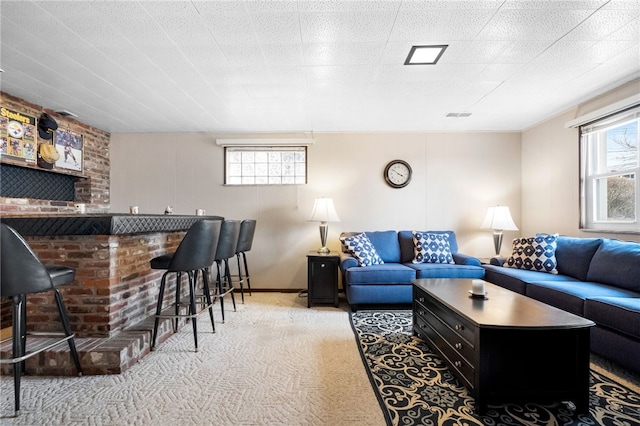 living area with visible vents, plenty of natural light, a bar, and carpet floors