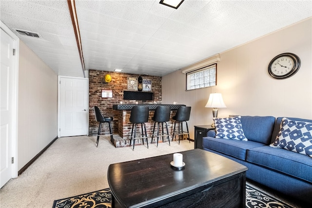 carpeted living area with visible vents, bar, and baseboards