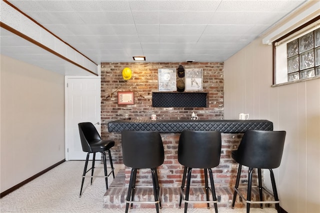 bar with carpet flooring, a bar, and baseboards