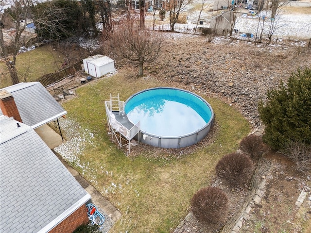 view of swimming pool with an outdoor structure, a storage unit, and fence