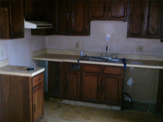 kitchen with a sink, range hood, and light countertops