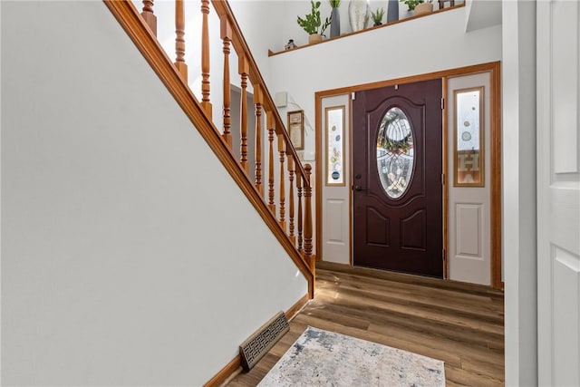 entryway featuring visible vents, stairway, baseboards, and wood finished floors