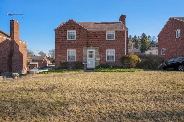 view of front facade featuring a front yard, brick siding, and a chimney