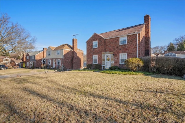 view of front of house with a front lawn, brick siding, and a chimney