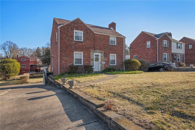 view of front of home with a front lawn, brick siding, and a chimney