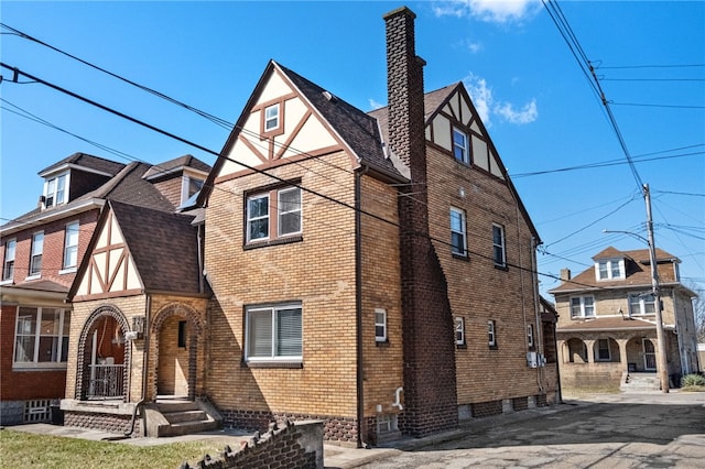 view of side of property with brick siding, roof with shingles, and a chimney