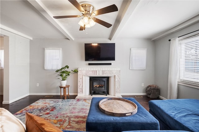 living area featuring beamed ceiling, wood finished floors, baseboards, and ceiling fan