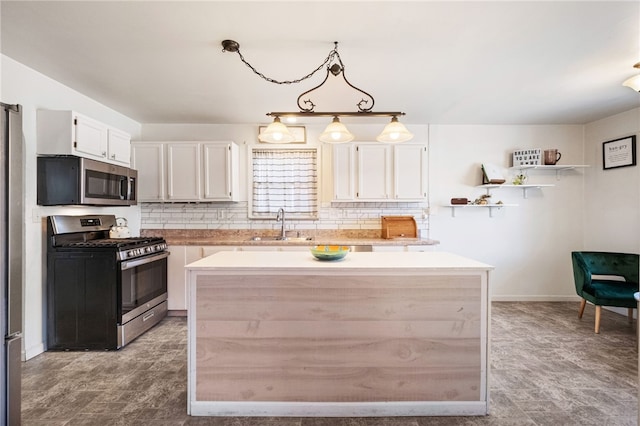 kitchen with backsplash, a kitchen island, white cabinets, stainless steel appliances, and a sink