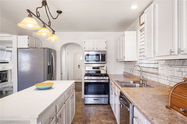 kitchen with light countertops, appliances with stainless steel finishes, arched walkways, white cabinetry, and a sink