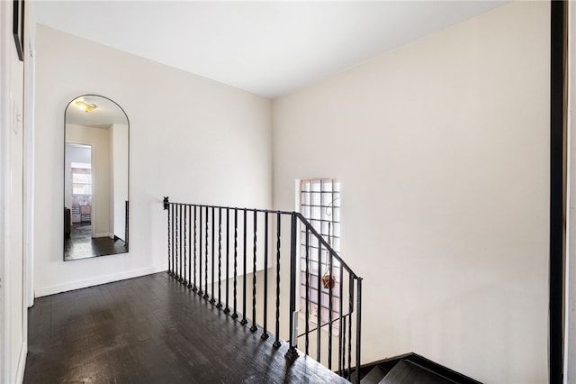 hallway featuring a wealth of natural light, baseboards, an upstairs landing, and dark wood-type flooring