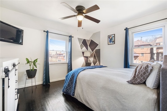 bedroom with multiple windows, ceiling fan, baseboards, and hardwood / wood-style flooring