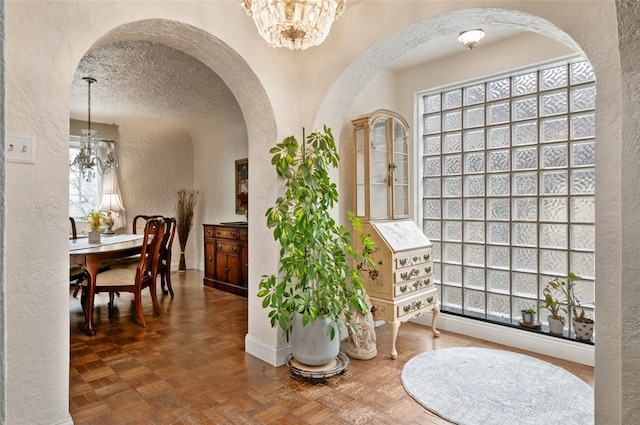 interior space with a chandelier, a healthy amount of sunlight, and a textured wall