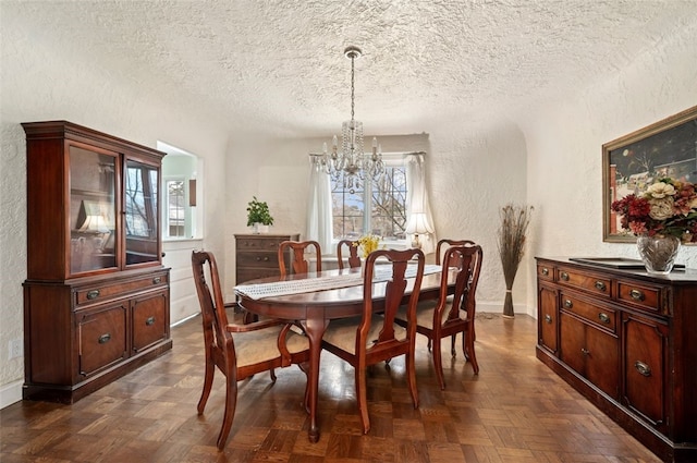 dining area featuring baseboards, a textured ceiling, an inviting chandelier, and a textured wall