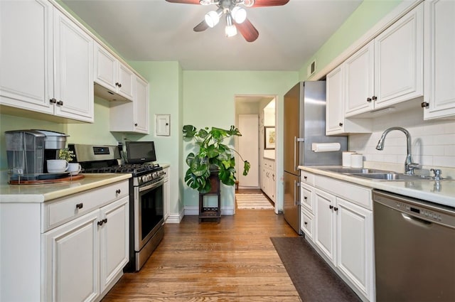 kitchen featuring a sink, stainless steel appliances, wood finished floors, and white cabinets