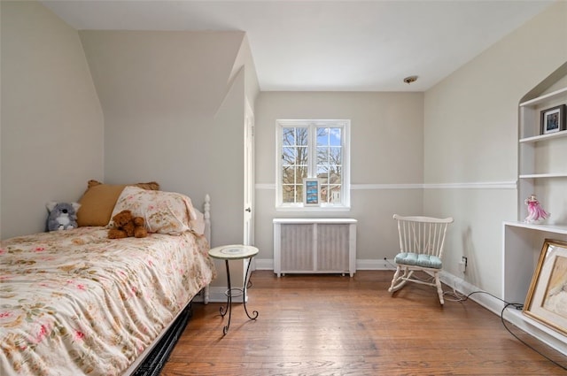 bedroom featuring radiator, baseboards, and wood finished floors