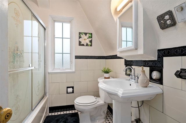 full bathroom featuring tile walls, toilet, a healthy amount of sunlight, and enclosed tub / shower combo