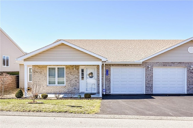 view of front of property with brick siding, a shingled roof, a front lawn, aphalt driveway, and an attached garage