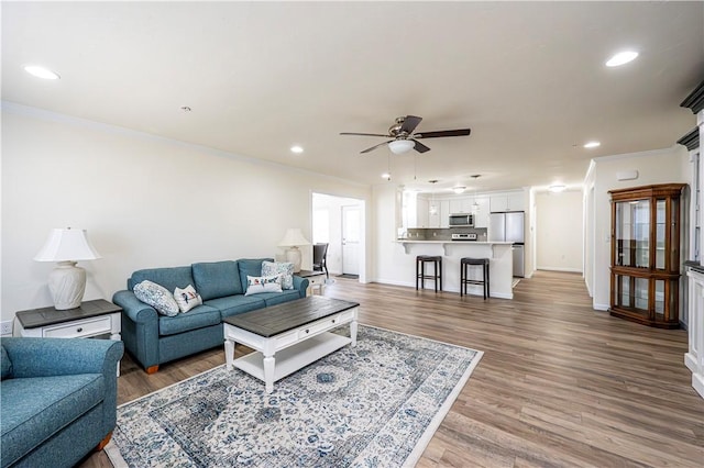 living room with recessed lighting, ornamental molding, and wood finished floors