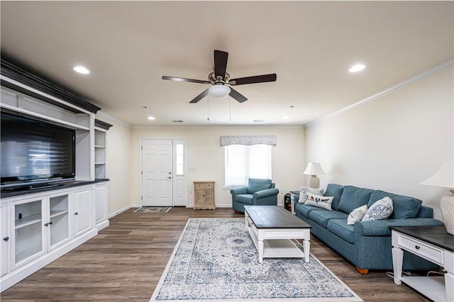 living area with ornamental molding, a ceiling fan, dark wood-style floors, recessed lighting, and baseboards