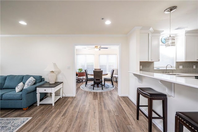 kitchen featuring a kitchen bar, light countertops, white cabinets, and backsplash