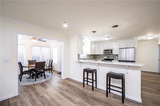 kitchen featuring crown molding, a breakfast bar area, dark wood-style floors, and stainless steel appliances