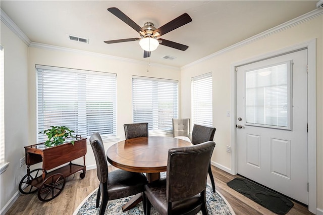 dining space featuring visible vents, ornamental molding, and light wood-style flooring