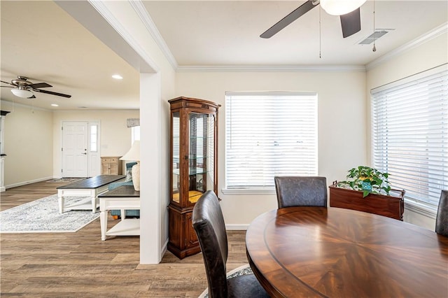 dining space featuring baseboards, wood finished floors, visible vents, and ornamental molding