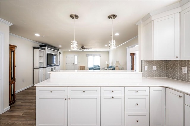 kitchen with tasteful backsplash, a peninsula, white cabinetry, and crown molding