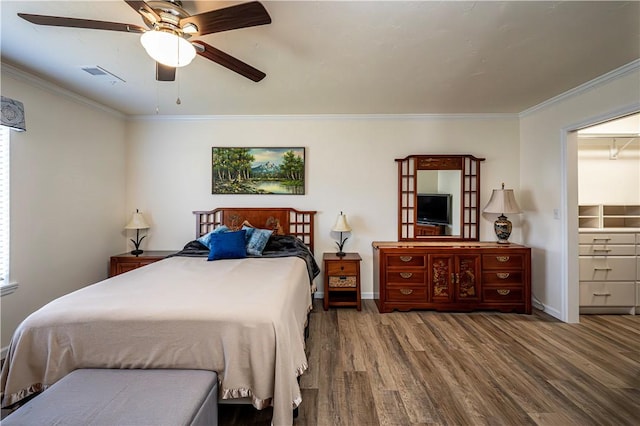 bedroom featuring visible vents, baseboards, wood finished floors, and ornamental molding