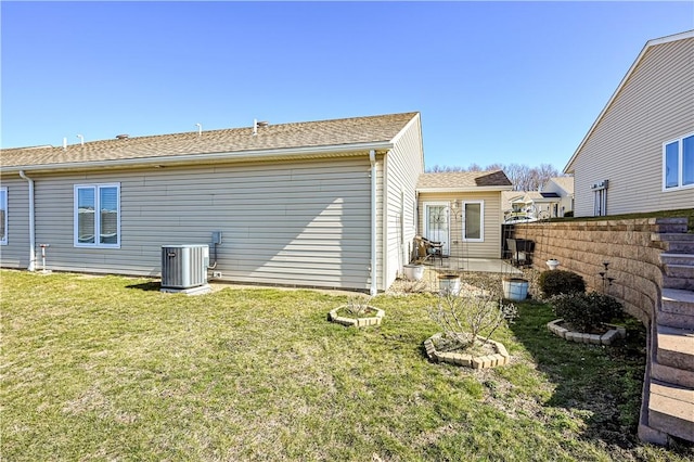 back of property with fence, a yard, a shingled roof, central air condition unit, and a patio area