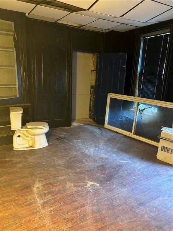 interior space featuring toilet, wood finished floors, and a paneled ceiling