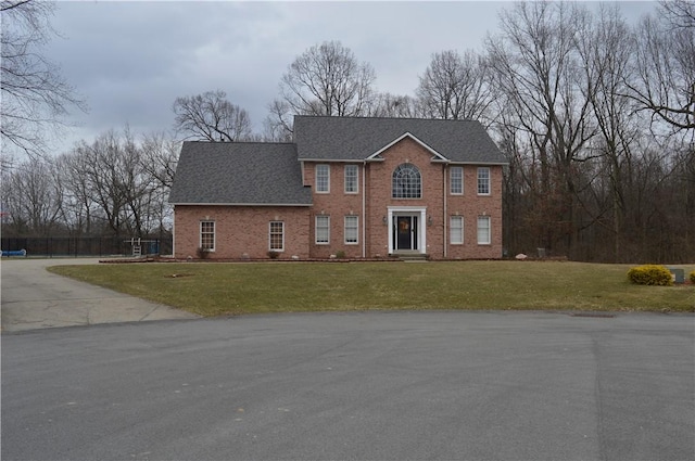 view of front of house with brick siding, a front lawn, and a shingled roof