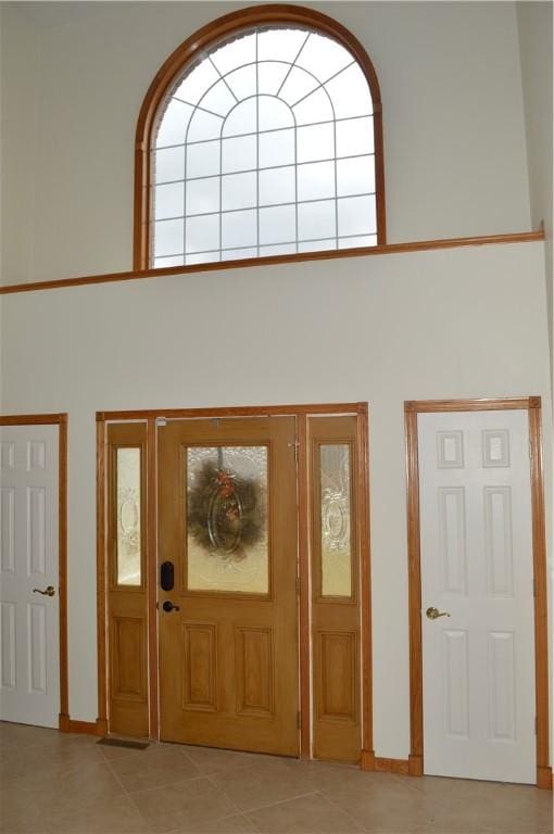 entryway with light tile patterned floors and a high ceiling