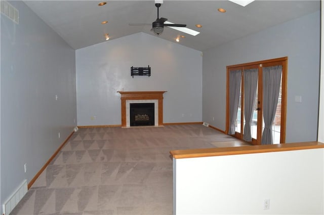 unfurnished living room with lofted ceiling with skylight, a fireplace with flush hearth, visible vents, and light carpet